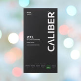A black box of Caliber 2XL - Extra Large Condoms (64mm Wide) is displayed against a blurred colorful bokeh background. The packaging reads "Made to Fit," indicates "64mm Wide," contains "12 Latex Condoms," and charts sizes from S to 3XL.